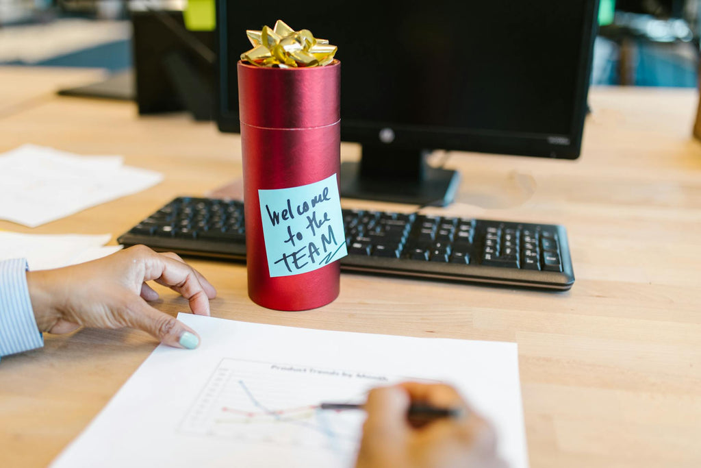 An employee gift on a work desk while hands are working on some paperwork nearby