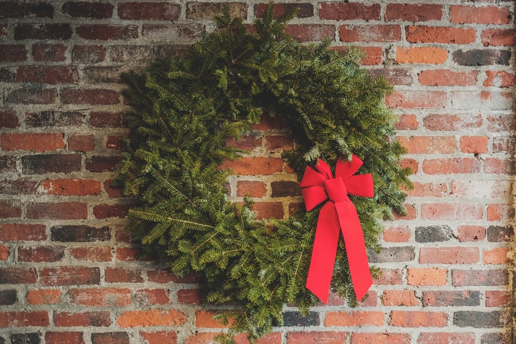 Holiday wreath with red bow on a brick wall, festive decor concept.